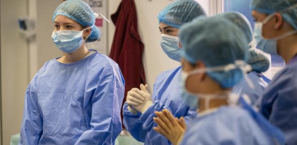 Pupils wear blue scrubs, masks, and caps stand attentively indoors, conveying focus and teamwork in a medical setting., Credit: Chad Cox for Cambridge Festival Pupils wear blue scrubs, masks, and caps stand attentively indoors, conveying focus and teamwork in a medical setting.