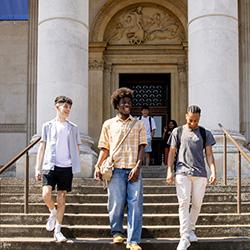 Three students walking down the steps of Fitzwilliam Museum, Cambridge.