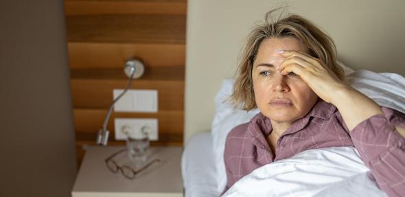 Sick woman lying in bed at home
