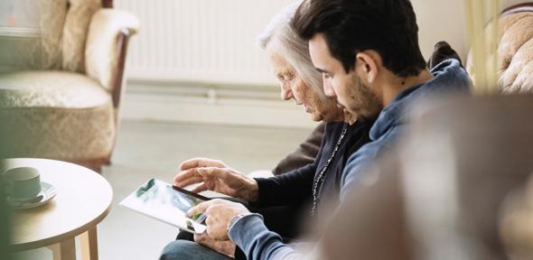 Caretaker and senior woman using digital tablet at nursing home - stock photo
