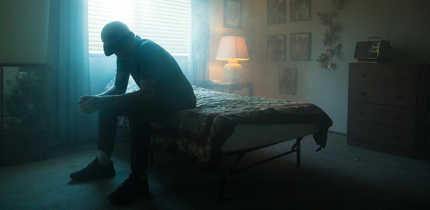 Man in black jacket sitting on bed
