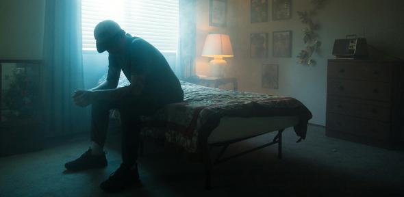 Man in black jacket sitting on bed