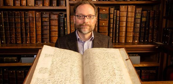 Dr Michael Edwards with Pepys Library MS 2861, one of Samuel Pepys' letter books, open at a letter written in September 1688 asking Captain Edward Stanley to sell an enslaved man in a plantation abroad
