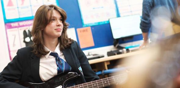 Adolescent girl plays the bass in school music class