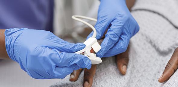 Nurse using pulse oximeter on hospitalised patient