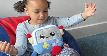Child with open arms and an AI powered soft toy on her lap.